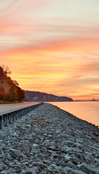 Sunset shining over water and a road beside the river